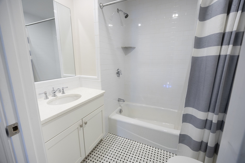 48 Spruce Street, Unit 1 Winchester, MA 01890 - Photo 13 of 29 a bathroom with a bathtub sink vanity granite and a toilet