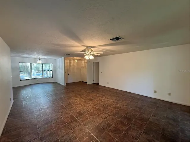 an empty room with windows and ceiling fan