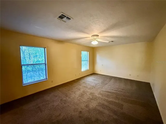 an empty room with windows and fan