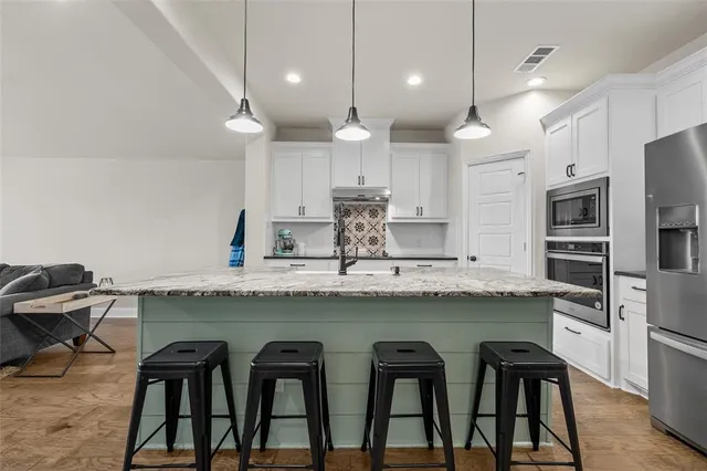 a kitchen with kitchen island granite countertop a table chairs microwave and cabinets