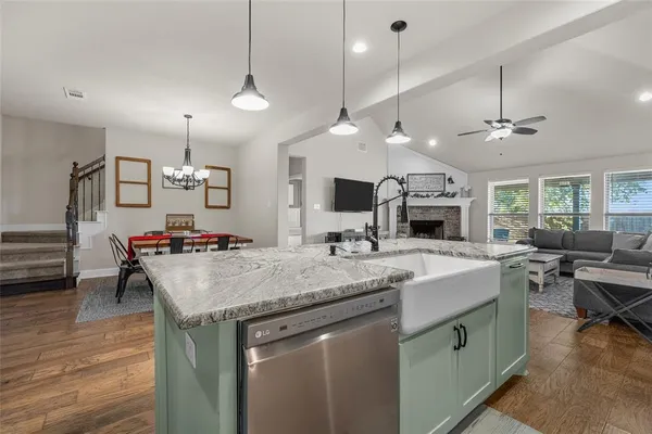 a kitchen with a stove a sink dishwasher a dining table and chairs with wooden floor