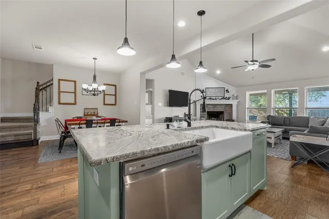 a kitchen with a stove a sink dishwasher a dining table and chairs with wooden floor