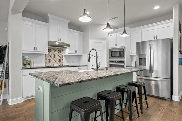 a kitchen with granite countertop a table chairs refrigerator and microwave