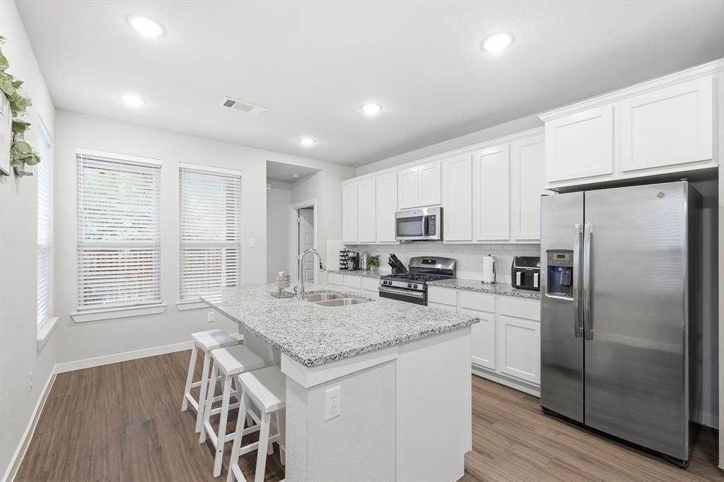 5582 Yarborough Drive Forney, TX 75126 - Photo 7 of 29 a kitchen with stainless steel appliances granite countertop a refrigerator a stove a sink and white cabinets with wooden floor