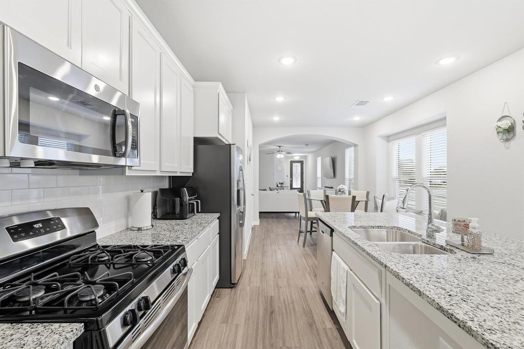 5582 Yarborough Drive Forney, TX 75126 - Photo 8 of 29 a kitchen with stainless steel appliances granite countertop a stove a sink dishwasher and a microwave oven with white cabinets