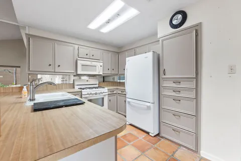 a kitchen with granite countertop a refrigerator and a stove top oven
