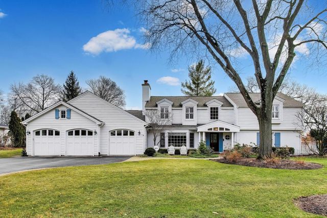 a view of a white house with a big yard and large trees