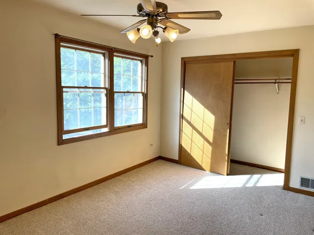 an empty room with windows and chandelier fan