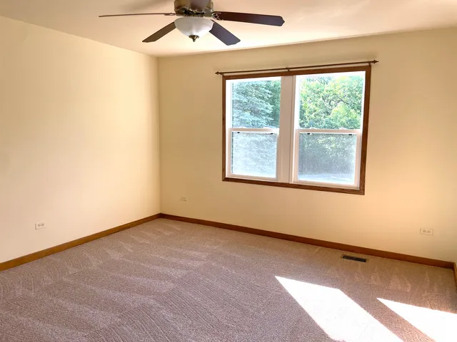 an empty room with a window and a ceiling fan