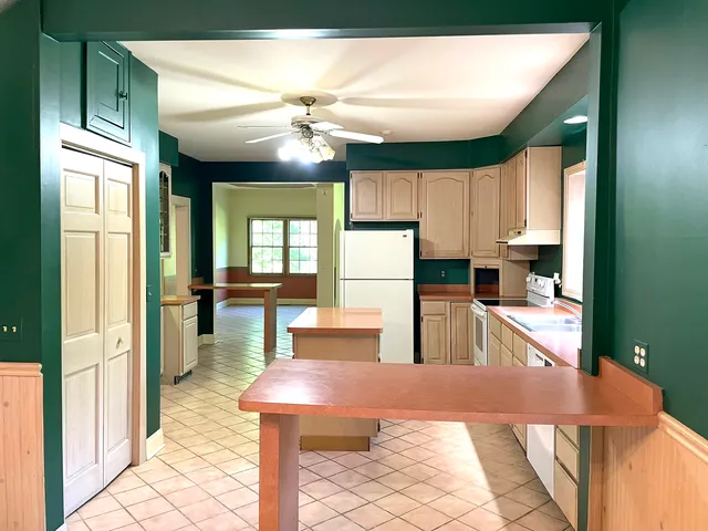 a view of a kitchen with kitchen island stainless steel appliances wooden floor dining table and chairs