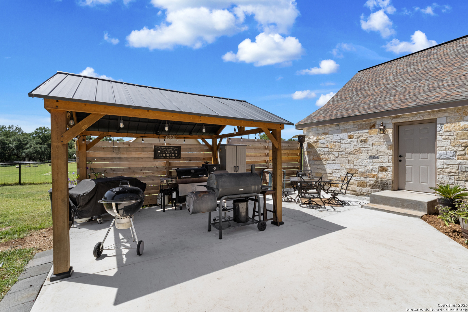 7040 Old Spring Branch Road Spring Branch, TX 78070 - Photo 33 of 43 a view of a patio with dining table and chairs with a barbeque grill and a yard