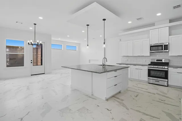 a large kitchen with granite countertop a sink and a stove top oven