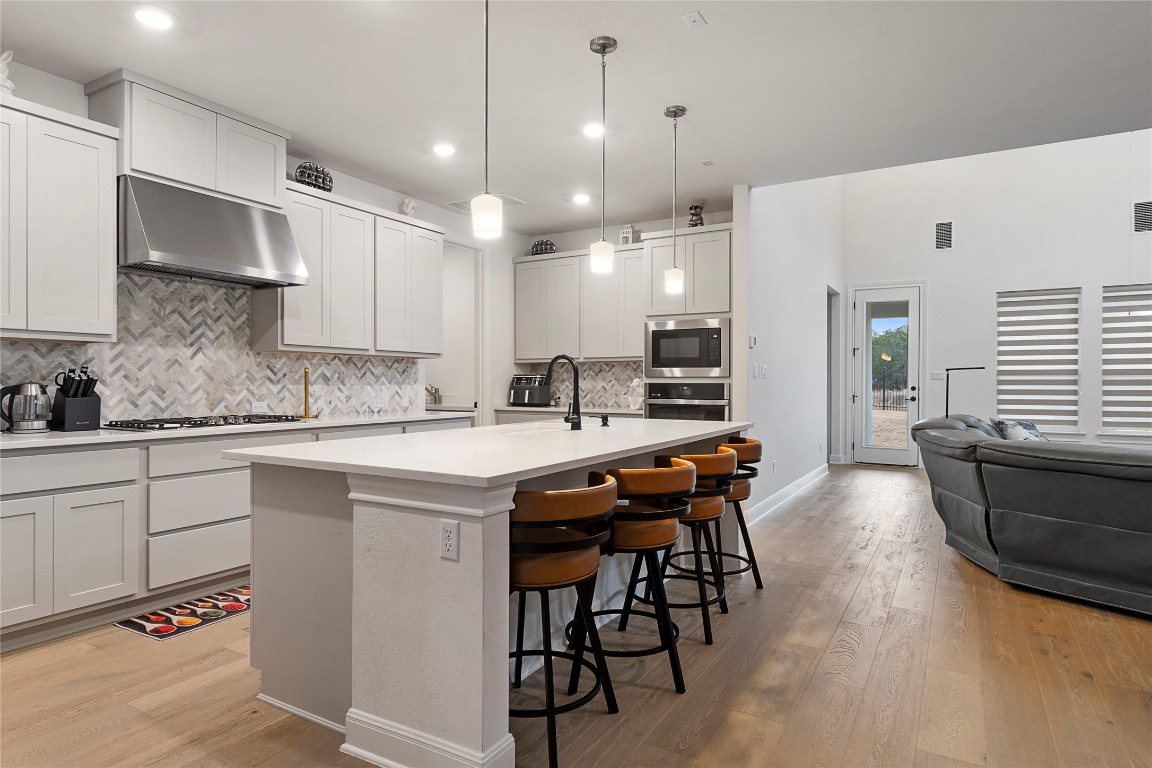 682 Two Creeks Lane Austin, TX 78737 - Photo 5 of 33 a kitchen with stainless steel appliances granite countertop a sink a stove a refrigerator and island with wooden floor