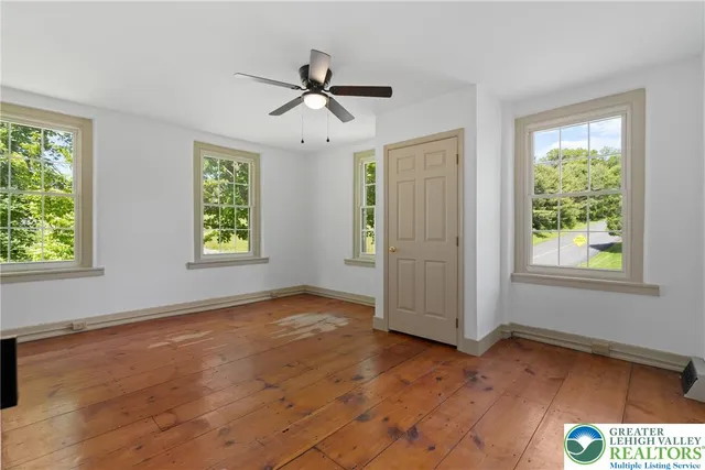 a view of empty room with wooden floor and fan