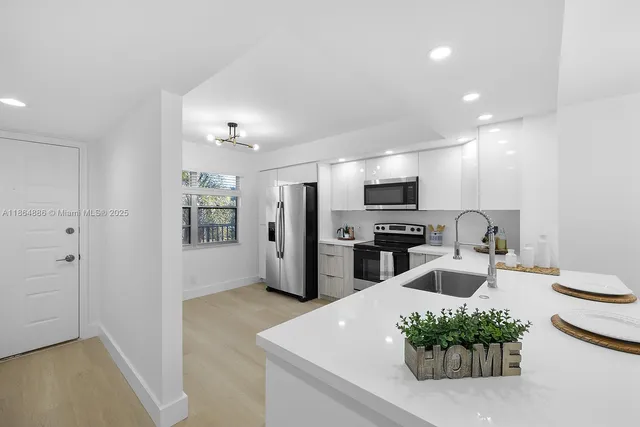 a kitchen with stainless steel appliances kitchen island granite countertop a refrigerator and a sink