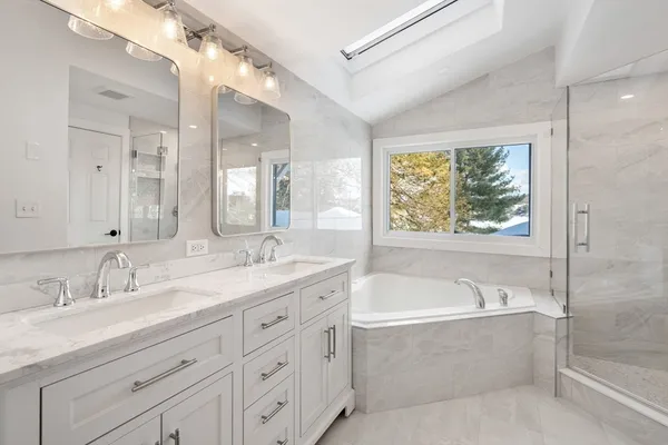 a bathroom with a granite countertop tub sink and mirror