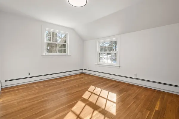a view of an empty room with a window and wooden floor