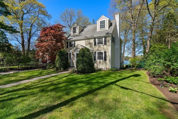 a view of a white house next to a yard with big trees