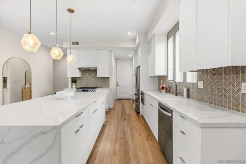 a large kitchen with kitchen island white cabinets and stainless steel appliances
