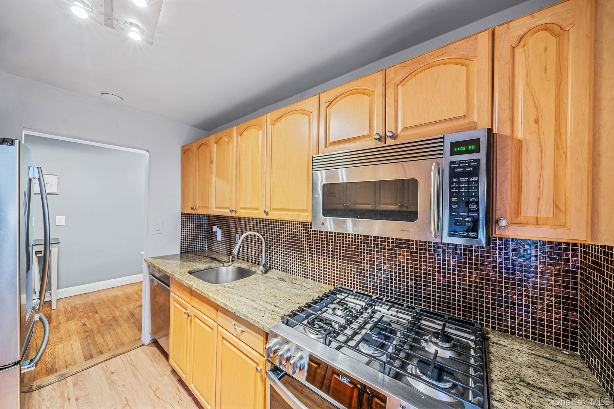 8 Terrace Circle, Unit 1G Great Neck, NY 11021 - Photo 6 of 17 a kitchen with stainless steel appliances a stove sink and cabinets