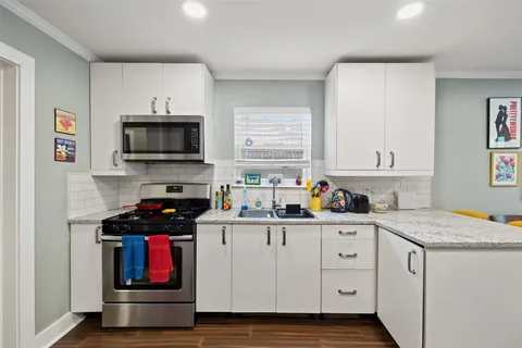 a kitchen with granite countertop a sink a stove and cabinets