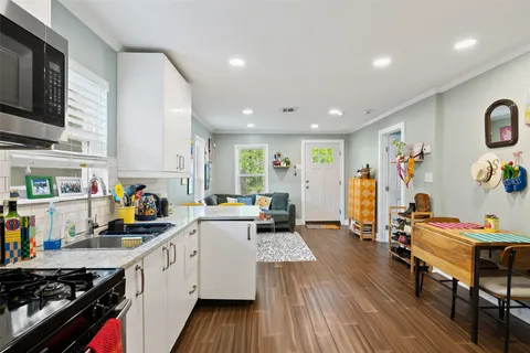 a kitchen that has a lot of cabinets a sink and wooden floor