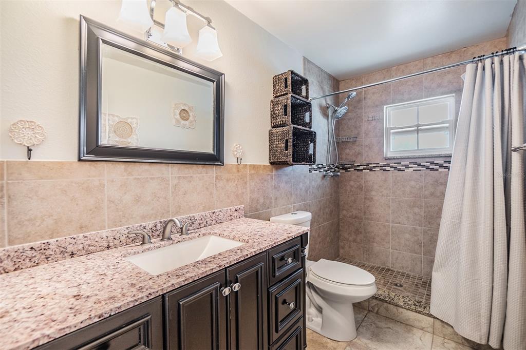 701 Poinsettia Road, Unit 306 Belleair, FL 33756 - Photo 13 of 25 a bathroom with a granite countertop sink a toilet and a shower