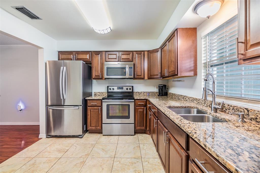 701 Poinsettia Road, Unit 306 Belleair, FL 33756 - Photo 2 of 25 a kitchen with granite countertop a sink stainless steel appliances and cabinets