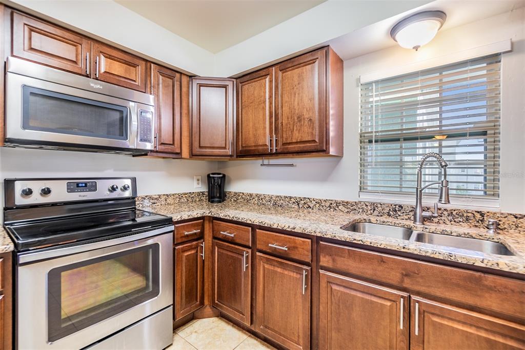 701 Poinsettia Road, Unit 306 Belleair, FL 33756 - Photo 4 of 25 a kitchen with stainless steel appliances granite countertop a sink stove and microwave