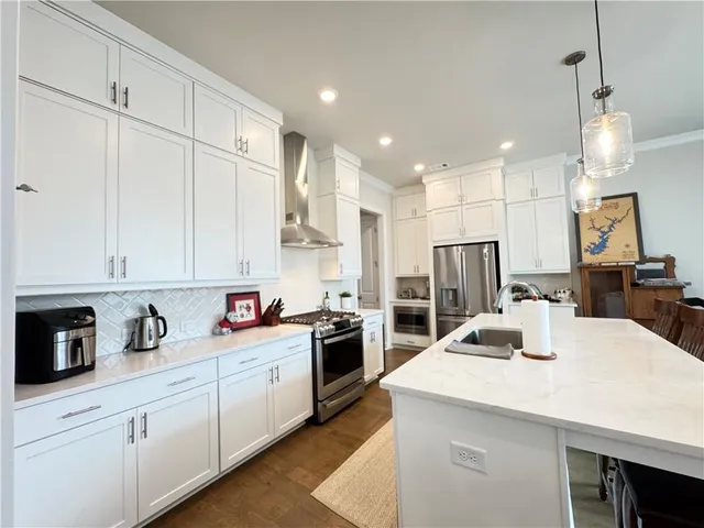 a kitchen with kitchen island a sink stainless steel appliances and white cabinets
