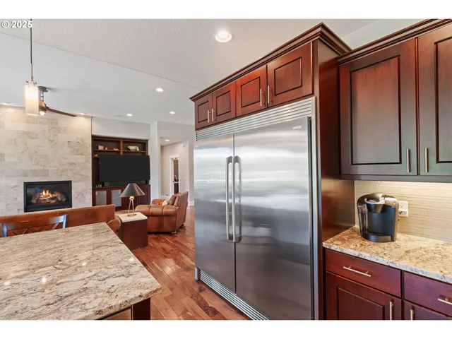 a kitchen with stainless steel appliances granite countertop a refrigerator a stove and a sink with wooden floor