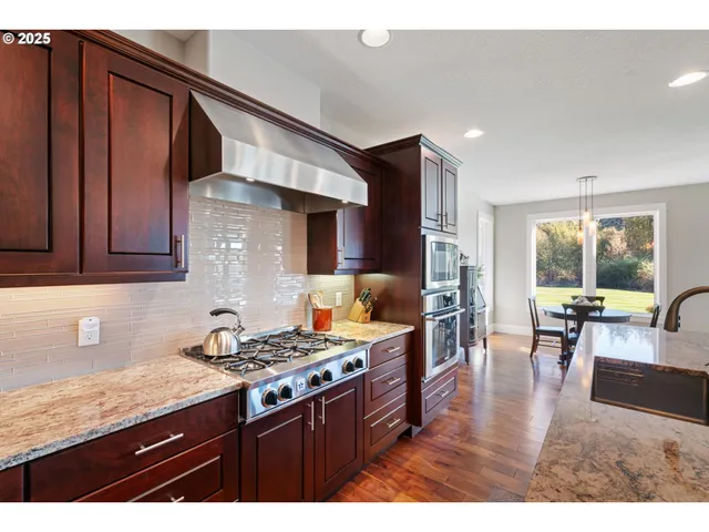 a kitchen with stainless steel appliances granite countertop a stove top oven a sink dishwasher and cabinets with wooden floor