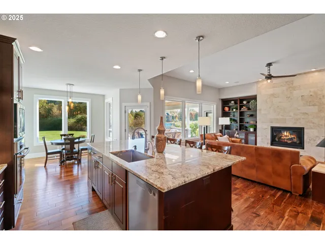 a living room with stainless steel appliances granite countertop furniture wooden floor and a view of kitchen