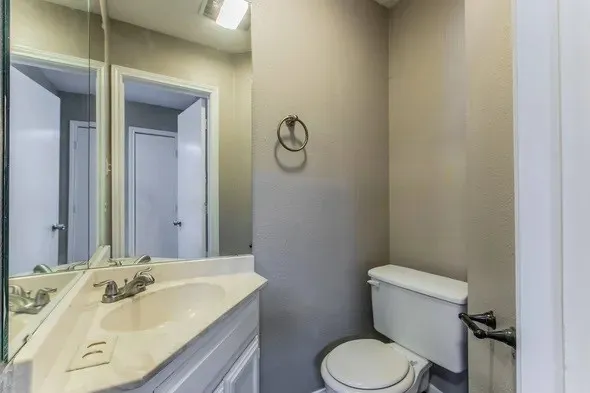 a bathroom with a granite countertop toilet sink and mirror