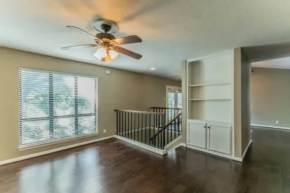 a view of a livingroom with wooden floor and a ceiling fan
