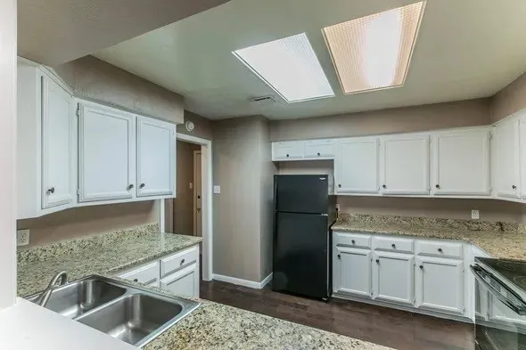 a kitchen with granite countertop a sink stainless steel appliances and cabinets