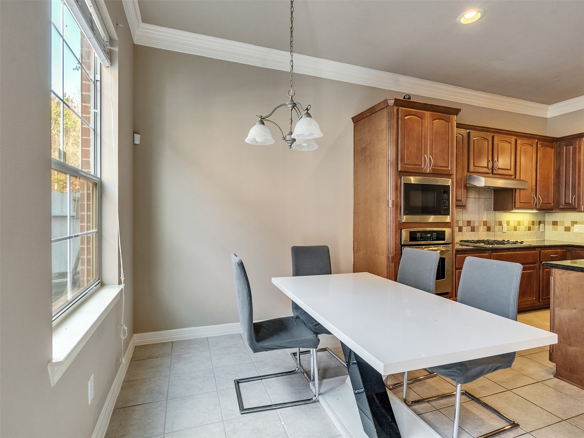 1502 Olive Place Houston, TX 77077 - Photo 11 of 27 Bright kitchen and breakfast area with modern lighting, tiled floors, and included dining set and stainless steel appliances.