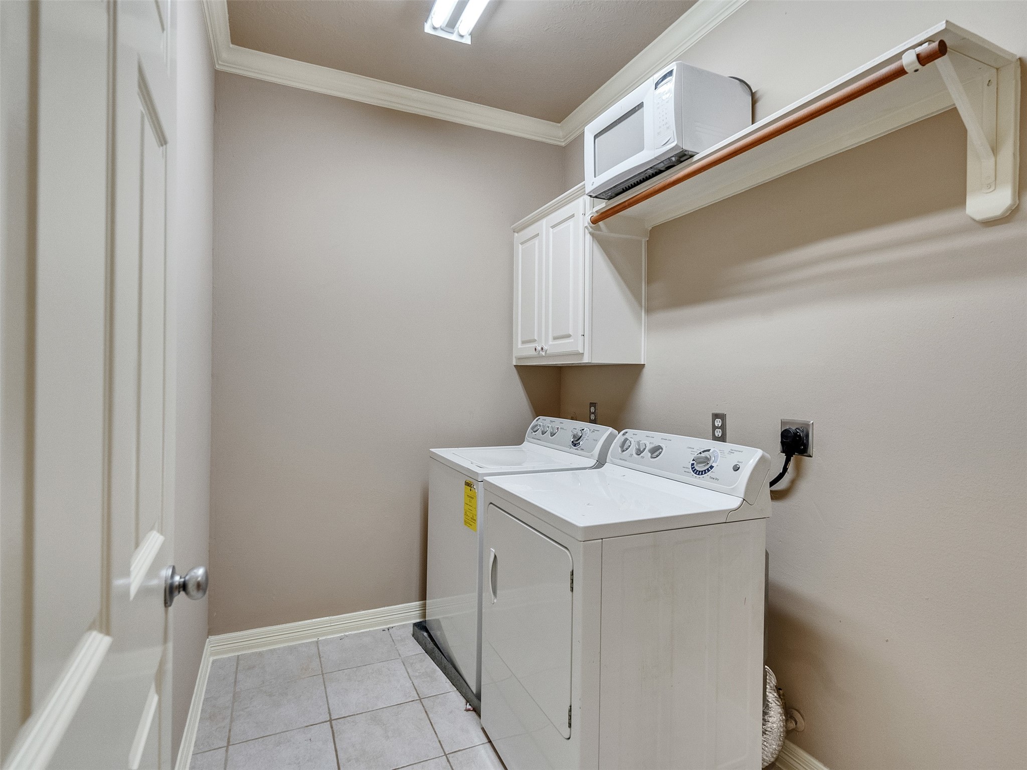 1502 Olive Place Houston, TX 77077 - Photo 20 of 27 Spacious utility room with included washer and dryer, featuring tiled flooring, overhead shelving, and built-in cabinetry for ample storage.