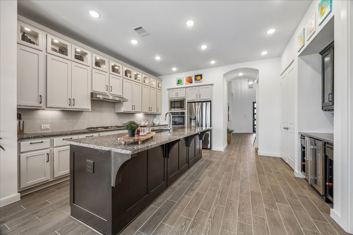 438 Livermore Street Webster, TX 77598 - Photo 7 of 34 a kitchen with stainless steel appliances granite countertop a stove top oven a sink dishwasher and a refrigerator with wooden floor