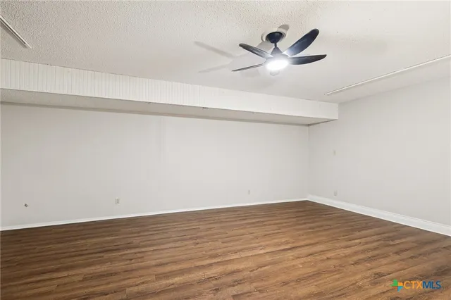 a view of a room with wooden floor and a ceiling fan