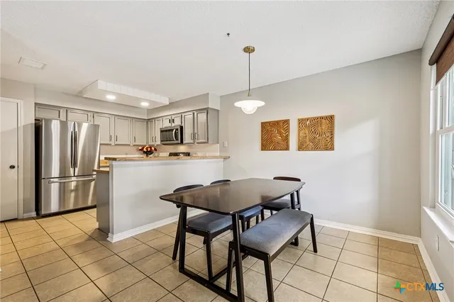 a kitchen with stainless steel appliances a refrigerator a stove a sink and chairs