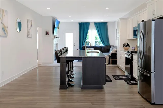 a kitchen with stainless steel appliances a refrigerator and a wooden floor