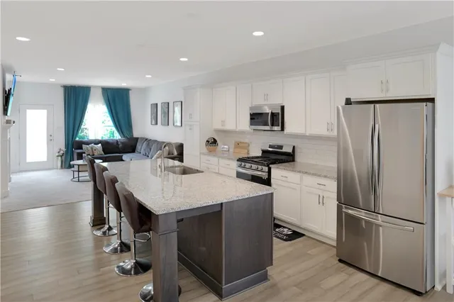 a kitchen with stainless steel appliances a refrigerator a stove a sink a dining table and chairs