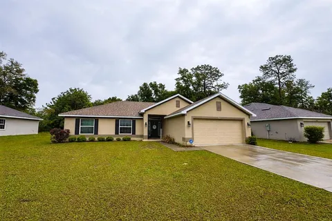 a view of a house with a big yard and large trees