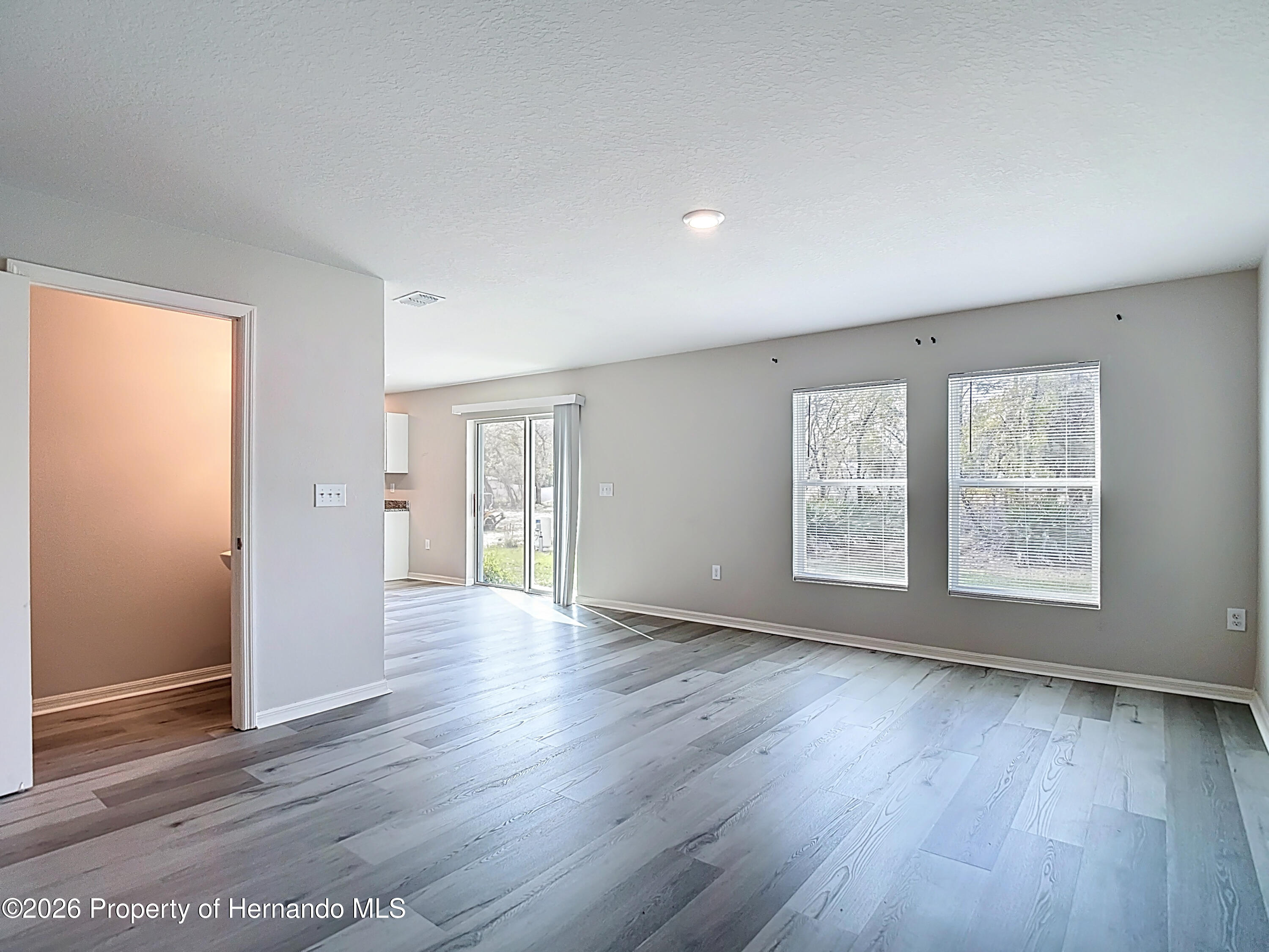 11374 Marcella Avenue Weeki Wachee, FL 34614 - Photo 17 of 70 a view of an empty room with wooden floor and a window