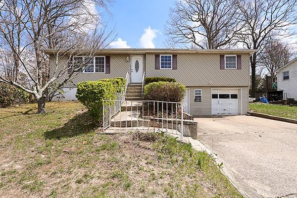 View of front of property with a front yard, a garage, and concrete driveway