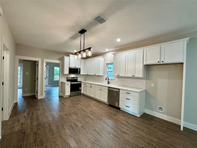 a kitchen with granite countertop white cabinets and stainless steel appliances
