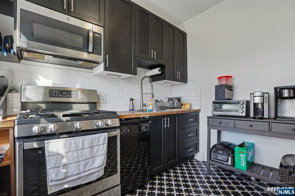82 Hackensack Street, Unit 6 Wood-Ridge, NJ 07075 - Photo 11 of 28 a kitchen with stainless steel appliances a stove microwave and cabinets
