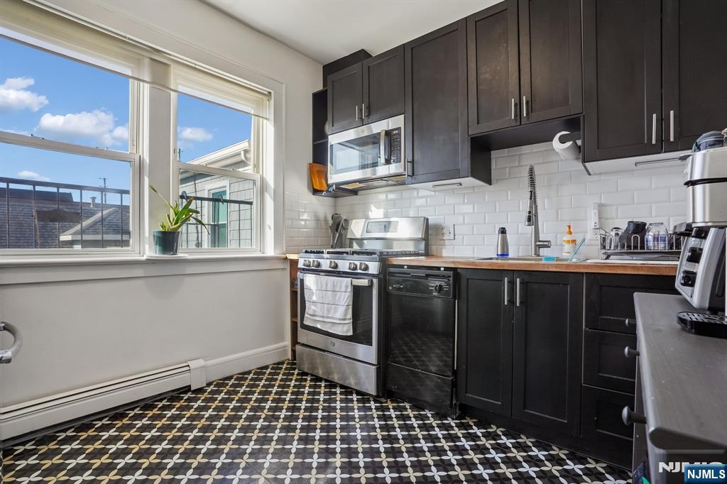 82 Hackensack Street, Unit 6 Wood-Ridge, NJ 07075 - Photo 12 of 28 a kitchen with stainless steel appliances a sink a stove a refrigerator cabinets and a window
