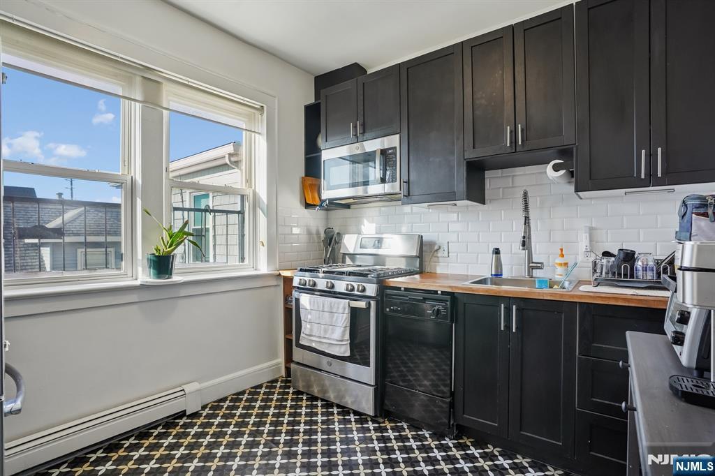 82 Hackensack Street, Unit 6 Wood-Ridge, NJ 07075 - Photo 8 of 28 a kitchen with stainless steel appliances a stove a sink and a microwave